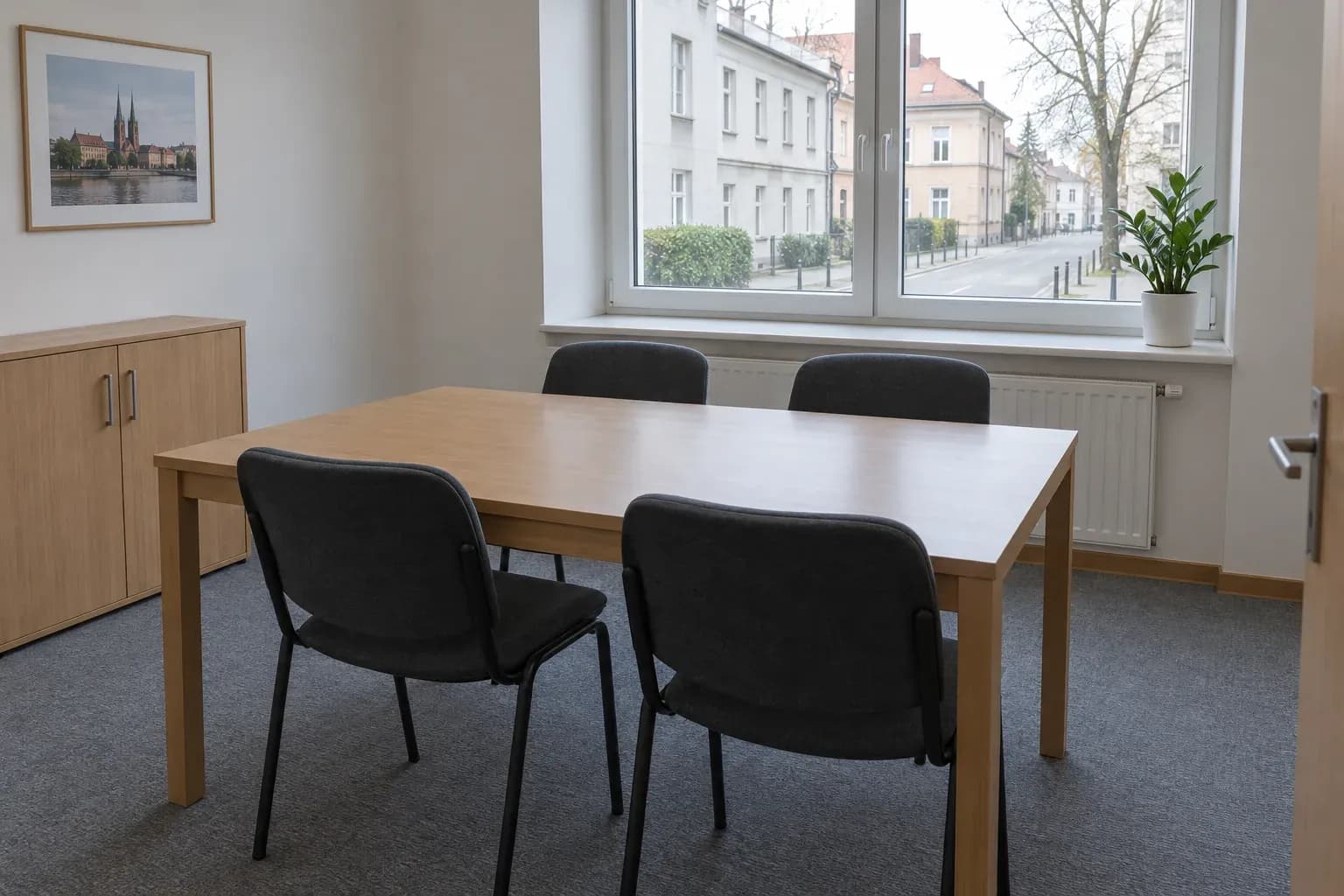 Sala spotkań z drewnianym stołem i czterema krzesłami przy oknie